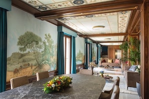 A spacious room with a large dining table, comfortable seating, and a mural on the wall.