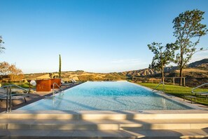 A rectangular swimming pool with a clear blue water surface, surrounded by a paved deck with steps leading into the pool.