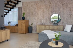 A modern living room with a staircase, wooden furniture, a grey sofa, and a round mirror. - Villa Ema, near the sea (Kanica)
