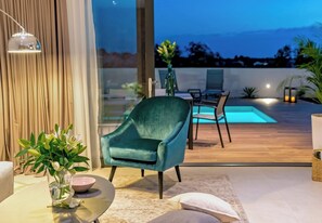 A modern outdoor seating area with a pool, a dining table, and a chair. - Villa Ema, near the sea (Kanica)