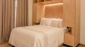 A bedroom with a bed, wooden headboard, and built-in shelving. - Don Manuel - Luxury Apartments & Studios (Oaxaca de Juárez)