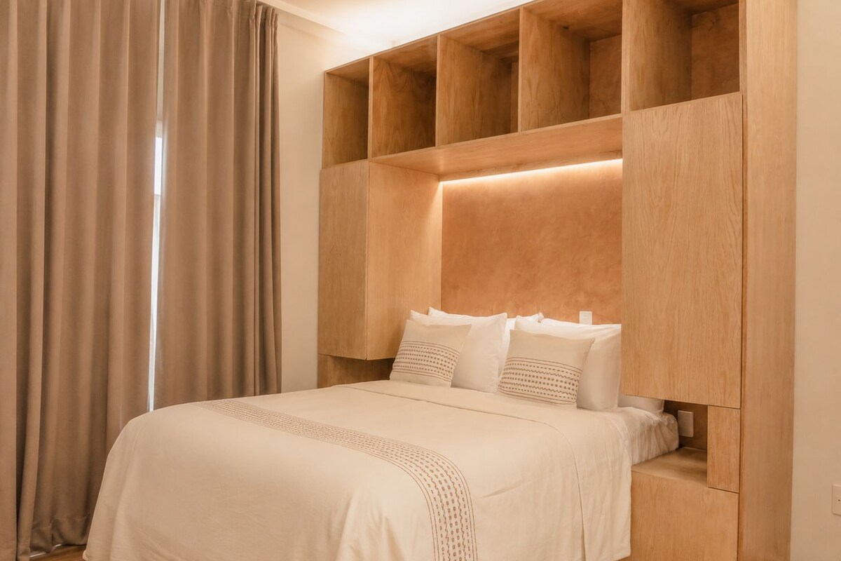 A bedroom with a bed, wooden headboard, and built-in shelving.