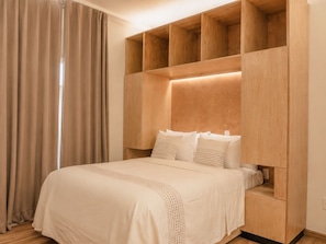 A bedroom with a bed, wooden headboard, and built-in shelving. - Don Manuel - Luxury Apartments & Studios (Oaxaca de Juárez)