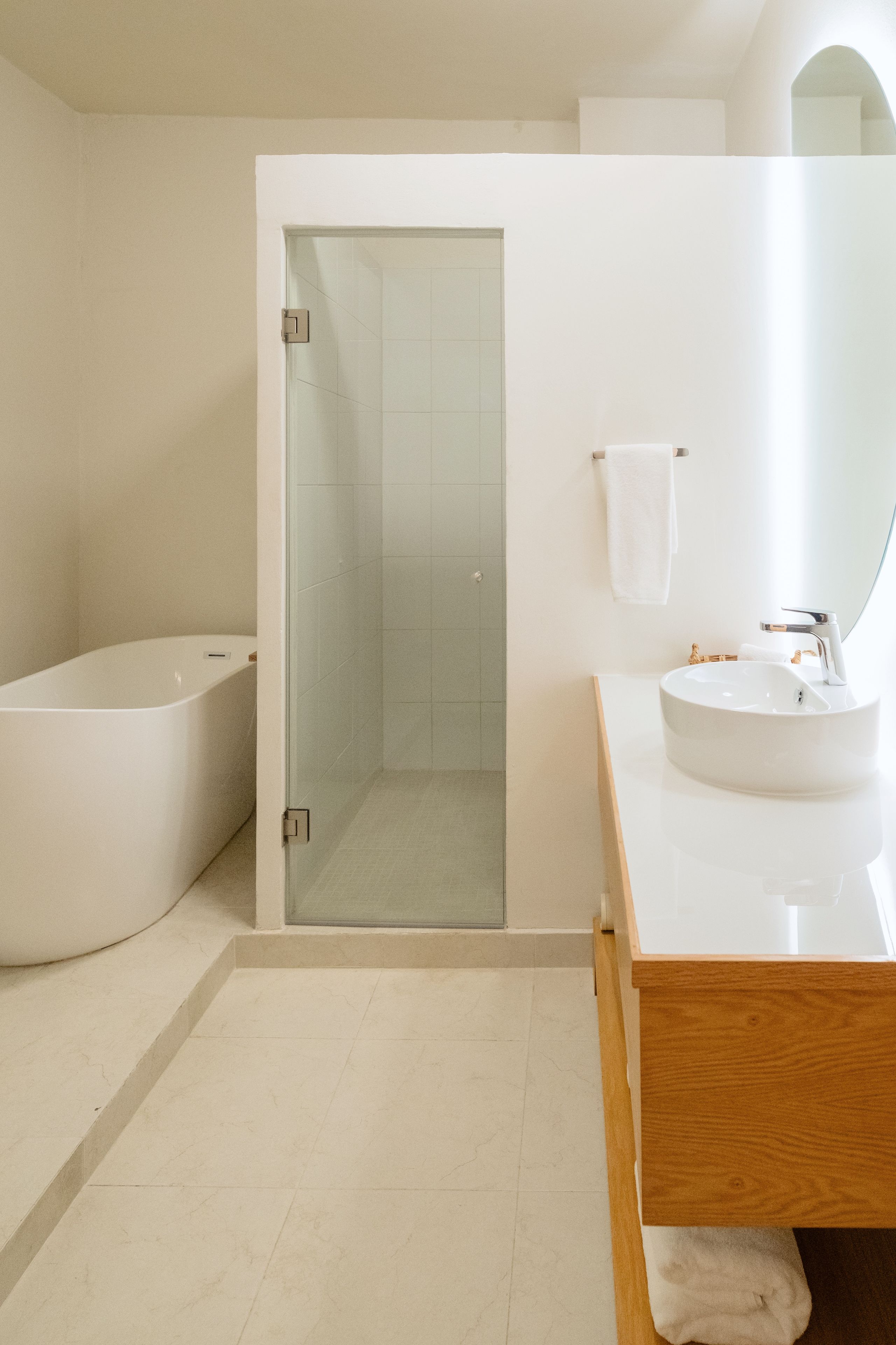 Un baño moderno con bañera, ducha envuelta en vidrio y tocador con lavabo y espejo.