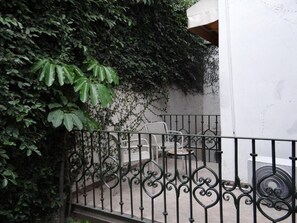 A balcony with a wrought iron railing, a white wall, and a small table with chairs. - Don Manuel - Luxury Apartments & Studios (Oaxaca)