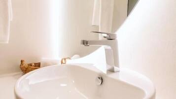 Un baño blanco con un lavabo redondo, un perchero y un espejo.