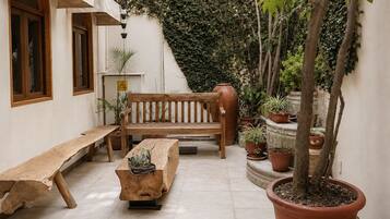 Un patio con un banco de madera, una mesa y plantas en macetas.