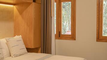A bedroom with a bed, wooden headboard, two windows with wooden frames, and an air conditioning unit.