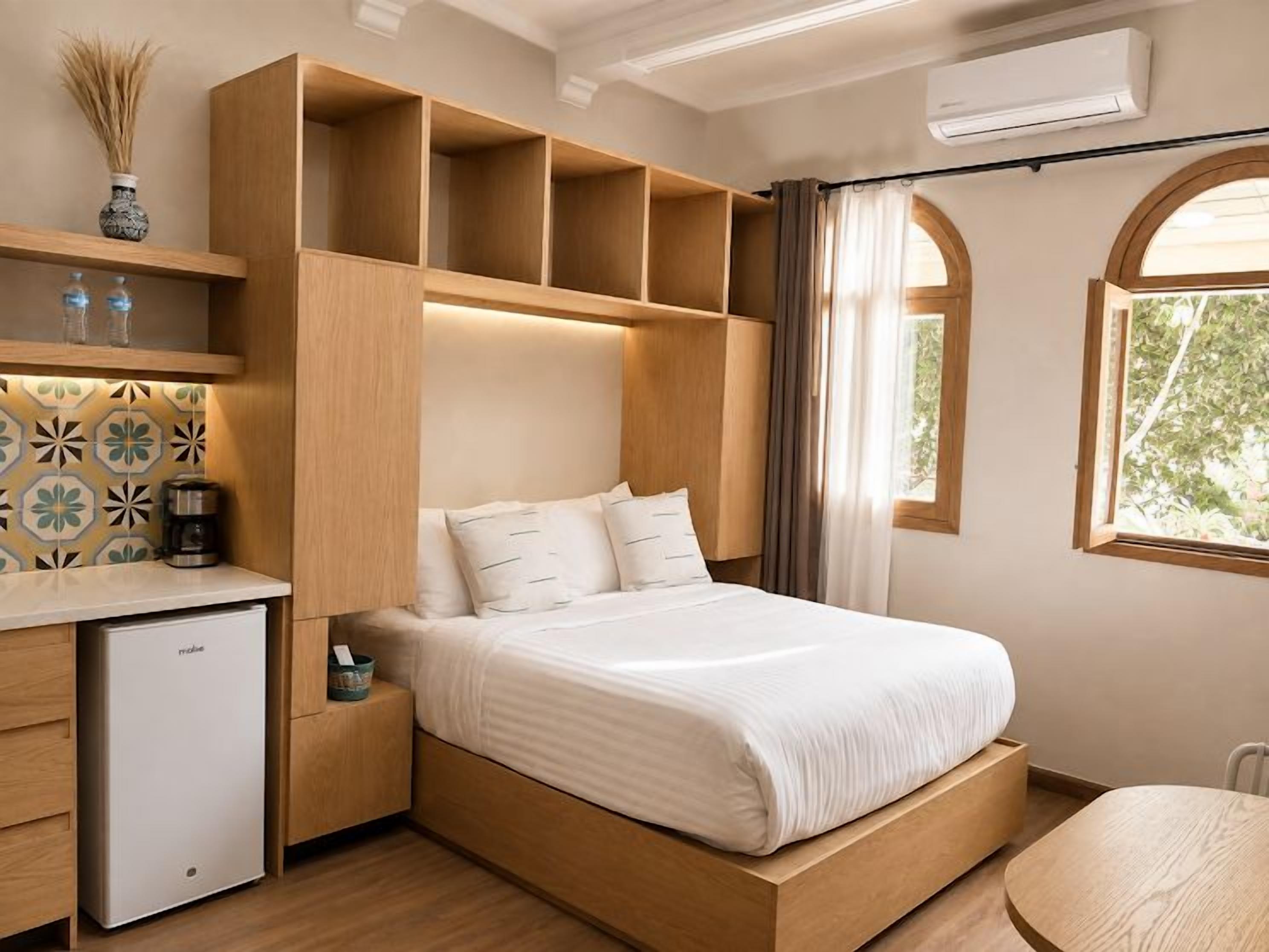 Un dormitorio con cama, estanterías empotradas, un escritorio pequeño y una ventana.