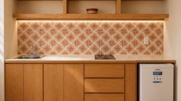 A kitchen with wooden cabinets, a stainless steel sink, a tiled backsplash, and a white refrigerator.