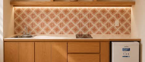 Eine Küche mit Holzausstattung, einem Edelstahlspülbecken, einer gefliesten Spritzschutzwand und einem weißen Kühlschrank.