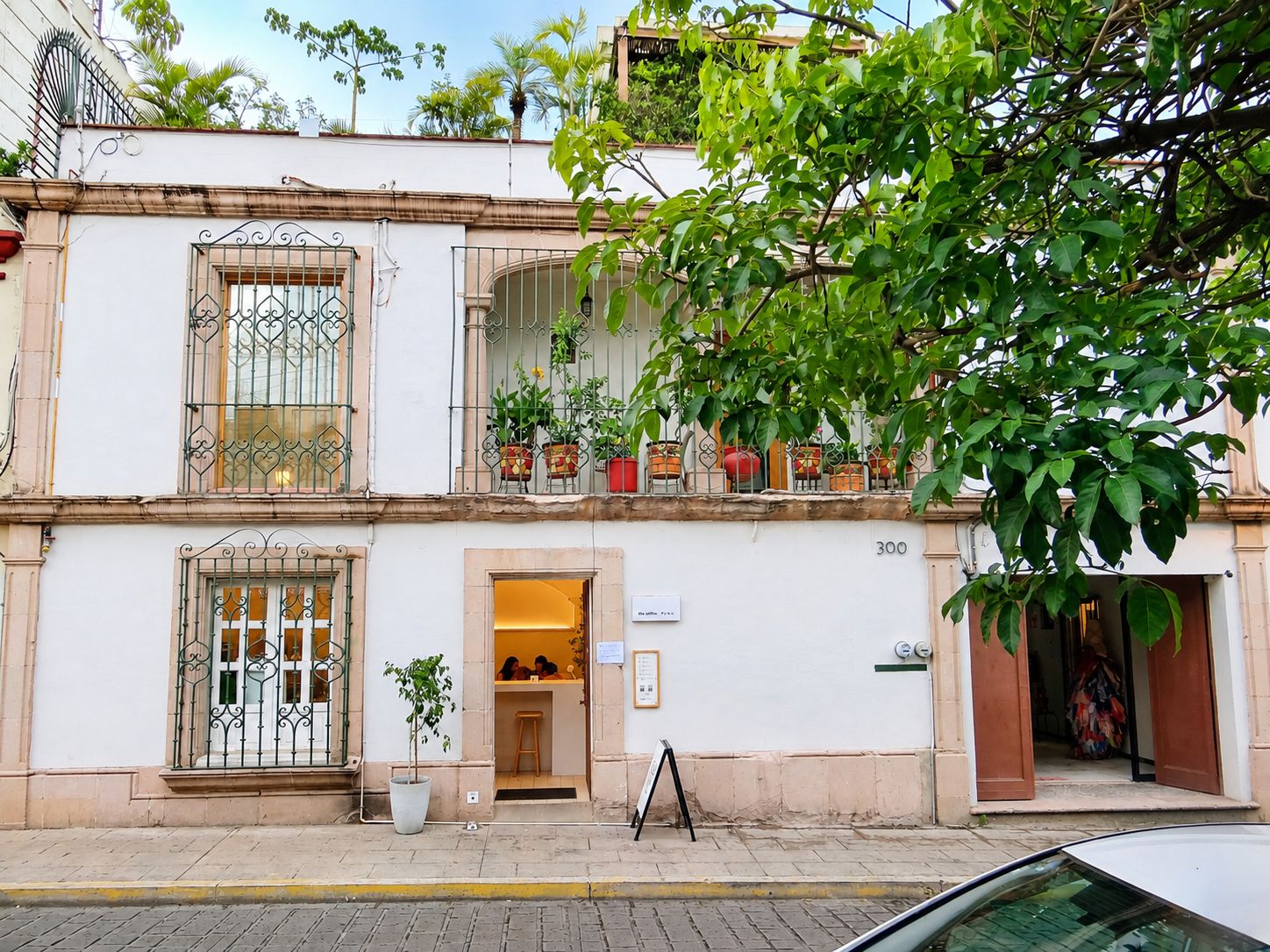 A two-story building with a balcony, potted plants, and a sign indicating the number 300.