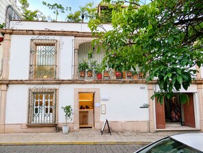 A two-story building with a balcony, potted plants, and a sign indicating the number 300. - Don Manuel - Luxury Apartments & Studios (Oaxaca)