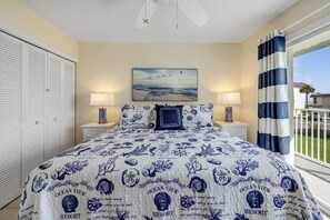 Ein Schlafzimmer mit einem Bett, zwei Nachttischlampen, einem Gemälde und Blick ins Freie.