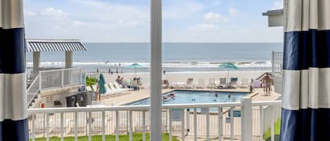 A pool area with a view of the beach and ocean.