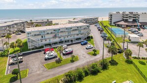 Un motel sulla spiaggia con diversi piani, un parcheggio e vista sull'oceano.