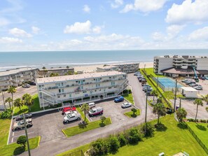 Ein Strandhotel mit mehreren Etagen, Parkplatz und Blick auf den Ozean.