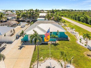 A large building with a flat roof, surrounded by palm trees and a flagpole with a flag. - Canal-Front 3BR Retreat with Amazing Pool & Coastal Charm (Saint James City)