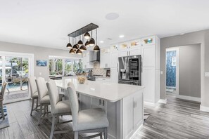 A modern kitchen with a central island, stainless steel appliances, and pendant lighting. - Canal-Front 3BR Retreat with Amazing Pool & Coastal Charm (Saint James City)