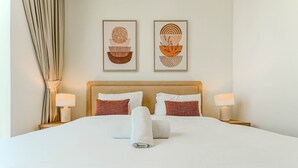 A hotel room with a large bed, two bedside lamps, a headboard, and two wall-mounted artworks.