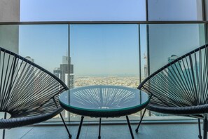 A balcony with two black wire-framed chairs and a glass table, overlooking a cityscape with high-rise buildings. - HAVN - 2 Bed in Downtown with Sea View (Dubai)