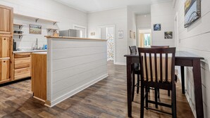 Eine moderne Küche mit Holzausbau, einem eingebauten Backofen und einer Essecke mit einem Holztisch und Stühlen.