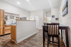 Una cocina moderna con armarios de madera, horno empotrado y zona de comedor con mesa y sillas de madera.