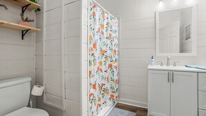 Ein Badezimmer mit Toilette, Waschbecken und Spiegel. Eine Duschvorhang mit Obstmusterung.