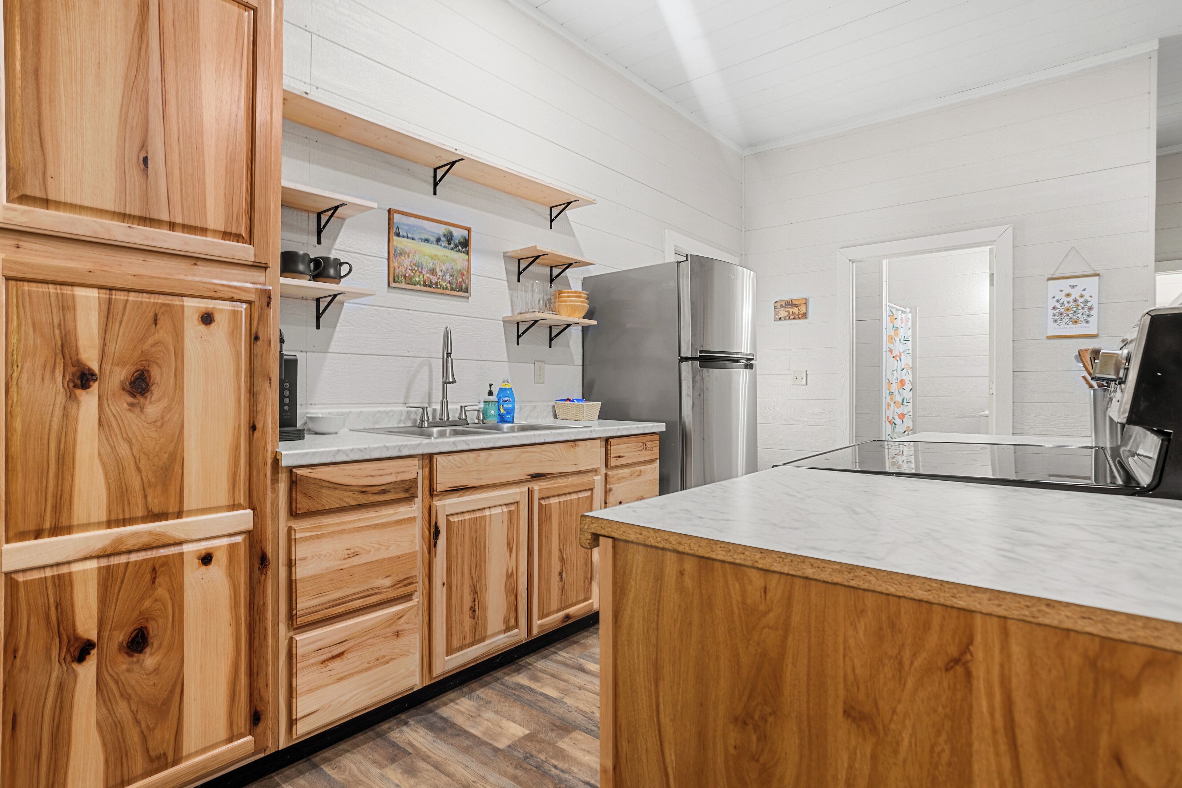 Una cocina con armarios de madera, un refrigerador de acero inoxidable y una encimera de mármol.