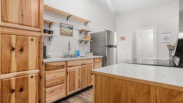 Una cocina con armarios de madera, un refrigerador de acero inoxidable y una encimera de mármol.