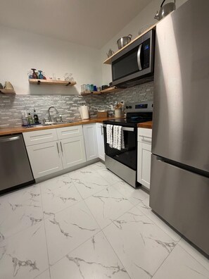 Eine moderne Küche mit weißen Schränken, einem Edelstahl-Kühlschrank, einer Mikrowelle und einem Herd.