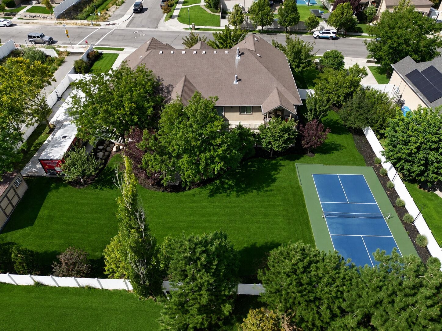 A residential area with a house surrounded by a well-maintained lawn and trees.