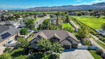 A residential area with houses, a well-maintained lawn, and a clear view of distant mountains.