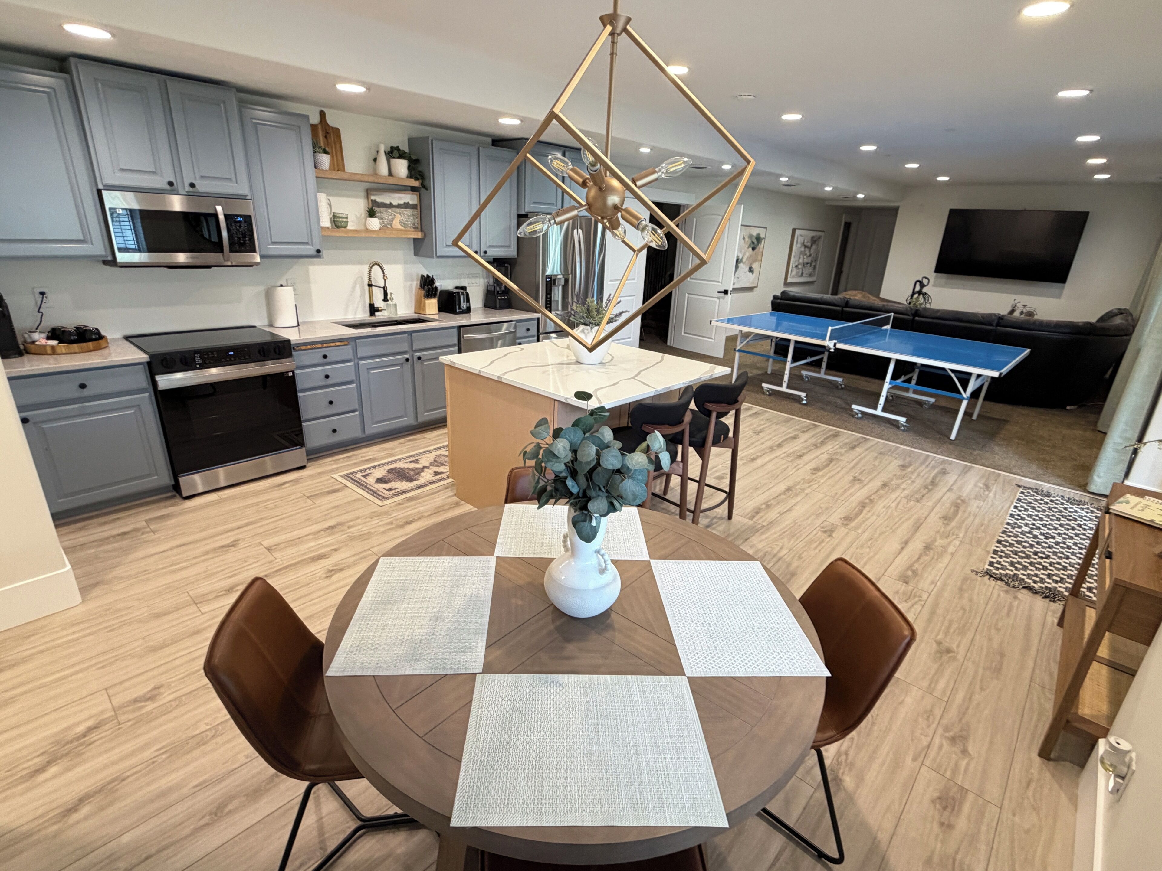 A modern kitchen with grey cabinets, a built-in microwave, and a dining area with a round table and chairs.