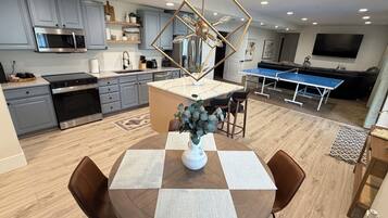 A modern kitchen with grey cabinets, a built-in microwave, and a dining area with a round table and chairs.