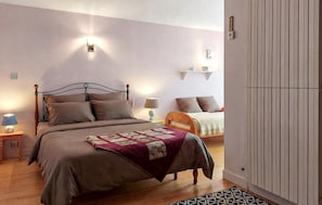 Een slaapkamer met een houten bed, een nachtkastje met een lamp en een wandlamp.