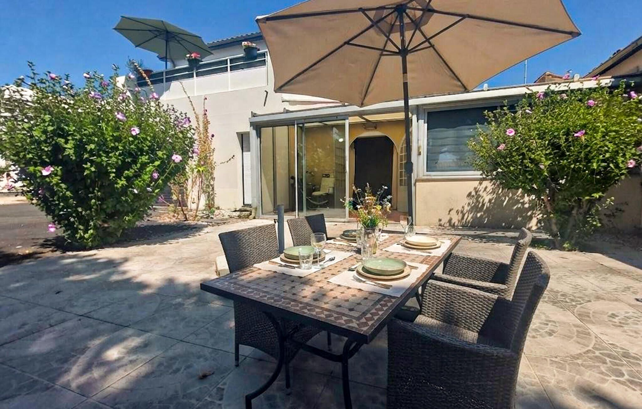Eine Terrassengruppe mit Esstisch, Stühlen und einem großen Sonnenschirm.