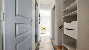 A hallway with a tiled floor leading to a room with a bed. - Charmante maison proche plage (Châtelaillon-Plage)