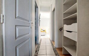 A hallway with a tiled floor leading to a room with a bed. - Charmante maison proche plage (Châtelaillon-Plage)
