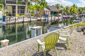 A tranquil pool area with a thatched-roof hut, surrounded by palm trees and a pebbled walkway. - Waterfront Escape - Canal Front, 50ft Dock, King Beds and Pet Friendly (Little Torch Key)