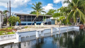 A residential property with a swimming pool, a covered patio, and a staircase leading to a covered deck. - Waterfront Escape - Canal Front, 50ft Dock, King Beds and Pet Friendly (Little Torch Key)