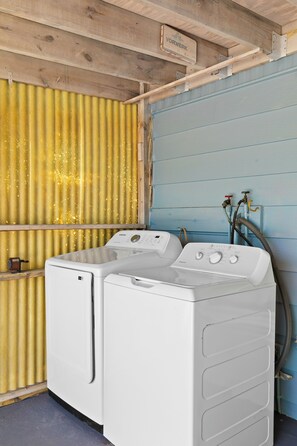 A laundry room with two white front-loading washing machines, a metal rack, and a hose. - Waterfront Escape - Canal Front, 50ft Dock, King Beds and Pet Friendly (Little Torch Key)