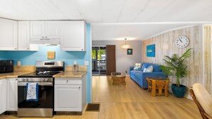 A modern kitchen with white cabinets, a stainless steel stove, and a blue accent wall. - Waterfront Escape - Canal Front, 50ft Dock, King Beds and Pet Friendly (Little Torch Key)
