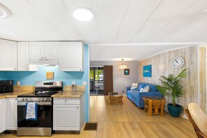 A modern kitchen with white cabinets, a stainless steel stove, and a blue accent wall. - Waterfront Escape - Canal Front, 50ft Dock, King Beds and Pet Friendly (Little Torch Key)