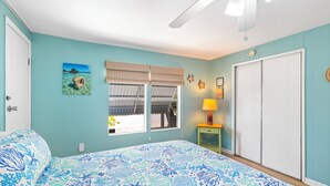 A bedroom with a bed, a window with a view, a ceiling fan, and a door. - Waterfront Escape - Canal Front, 50ft Dock, King Beds and Pet Friendly (Little Torch Key)