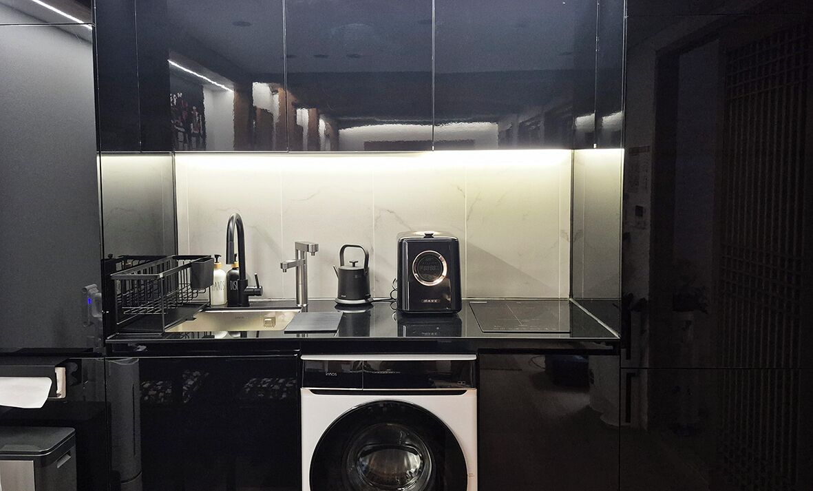 Une cuisine compacte équipée d’un lave-linge, d’une machine à café et d’un évier.