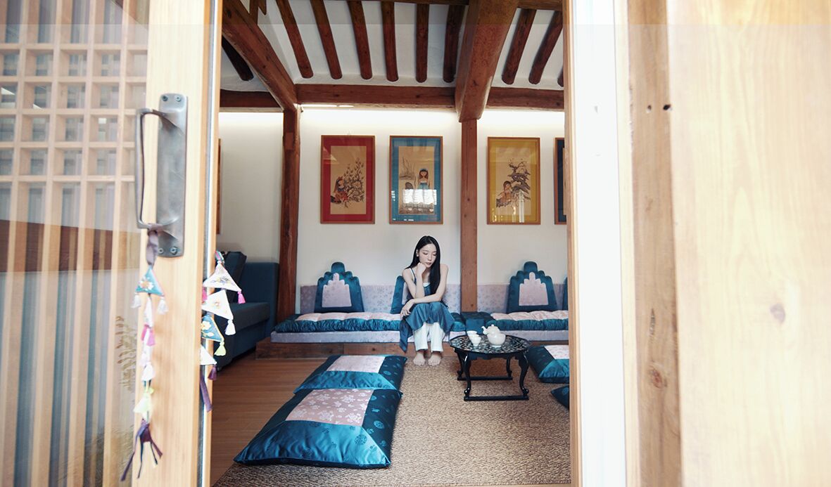 A room with a wooden ceiling, a sofa set, a small table, and wall-mounted artwork.
