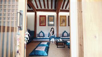 A room with a wooden ceiling, a sofa set, a small table, and wall-mounted artwork.