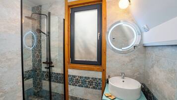Une salle de bain avec une douche à parois de verre, un miroir à cadre en bois et un miroir rond fixé au mur.