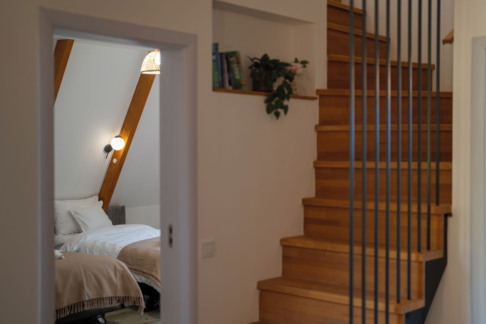 A bedroom with a bed, a nightstand, a bedside table, and a wall-mounted lamp.